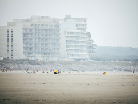 Large apartment building with blurred silhouettes of people enjoying the beachの写真素材