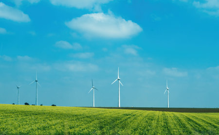 Idyllic field with yellow-colored landscape and multiple windmills generating electricity against a...