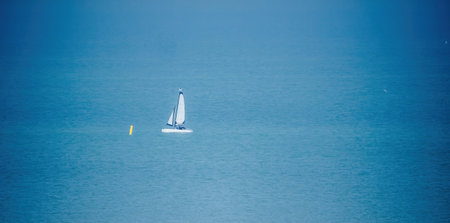 A tranquil scene unfolds with a small boat on the serene blue waters of the ocean, exuding a...