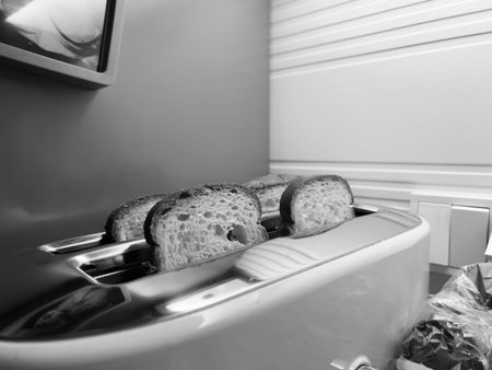 A classic black and white photograph of four slices of bread snugly fitted into a toaster,...