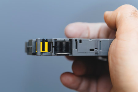 Side profile of a handheld printer labeler tape cartridge, displaying its compact design with a yellow and black stripe for alignment and functionality.の写真素材