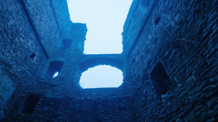A haunting view of a castle's interior ruins under a blue-tinted light, with crumbling stone walls, arched windows, and a mysterious atmosphere.の写真素材