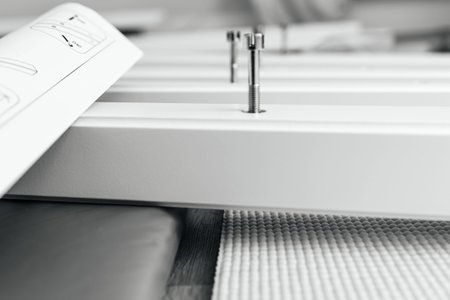 A close-up black and white shot of a furniture assembly process, showing bolts partially inserted...