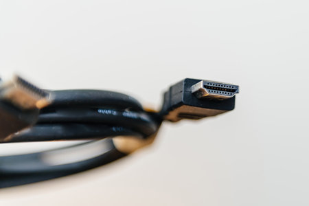 A close-up macro shot of an HDMI connector showing its metallic pins and black plastic housing, with the coiled cable visible in the background.の写真素材
