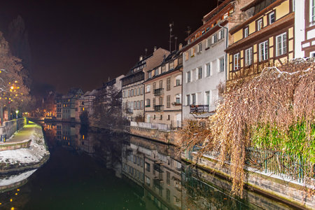 Nightfall casts a serene glow over the tranquil waters and quaint buildings of Strasbourg Petite Franceの写真素材