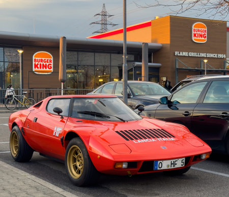 Offenburg, Germany - Apr 5, 2025: Bright red classic Lancia Stratos HF with gold wheels parked near...