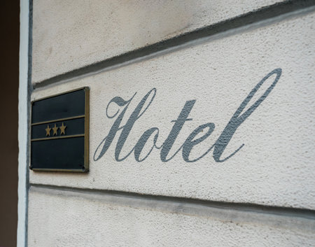 A three-star hotel sign mounted on a beige textured wall with large cursive writing displaying the word Hotel, captured on a street in Baden-Baden, Germanyの写真素材