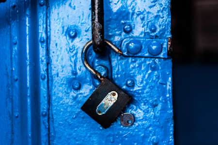 Padlock with key hanged on an open doorの写真素材