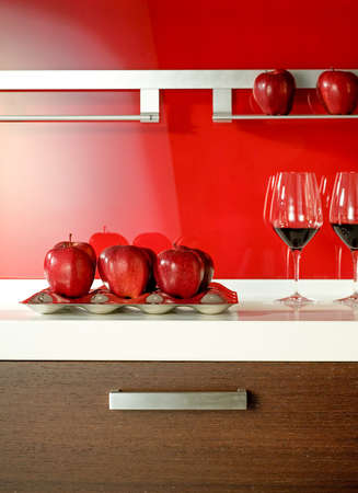 red apples and red wine glasses on the floor of a modern kitchenの写真素材