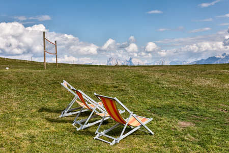 Deck chairs on a mountain meadow in the background of the Dolomitesの写真素材
