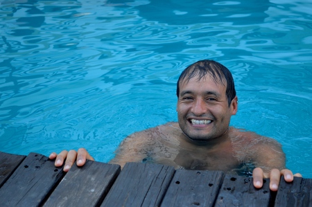 Young man enjoys the water of the poolの写真素材