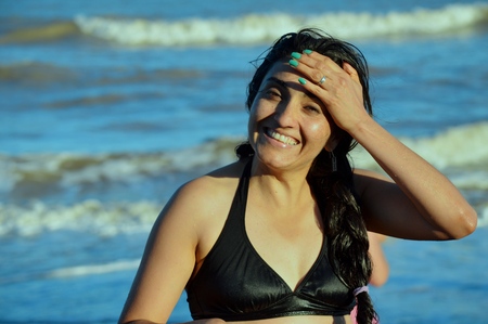 Beautiful model poses for the happy camera on the beachの写真素材