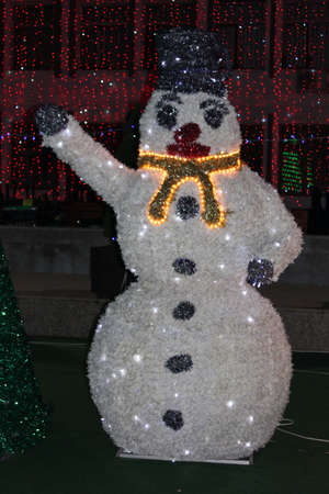 Snowman with a lot of lights near a Christmas Treeの写真素材