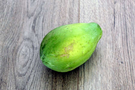 Unripe papaya fruit isolated on wood backgroundの写真素材