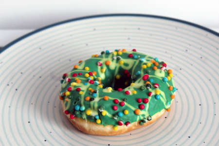 One green glazed doughnut isolated on blue circles plateの写真素材