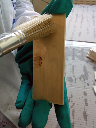 A technician with a paintbrush primer a piece of woodの写真素材