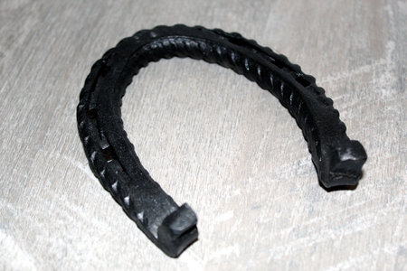 Black forged iron horseshoe on wooden floorの写真素材