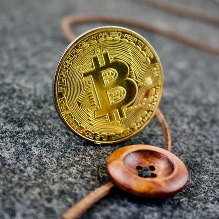 Cryptocurrency gold physical bitcoin coin and wooden button.のeditorial素材