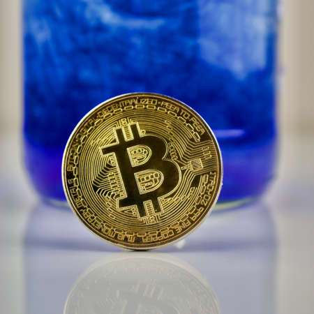 Cryptocurrency physical gold bitcoin coin on blue patternのeditorial素材