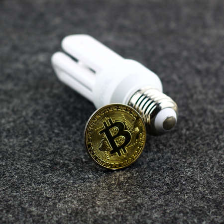 Cryptocurrency gold bitcoin coin with a white eco bulbのeditorial素材
