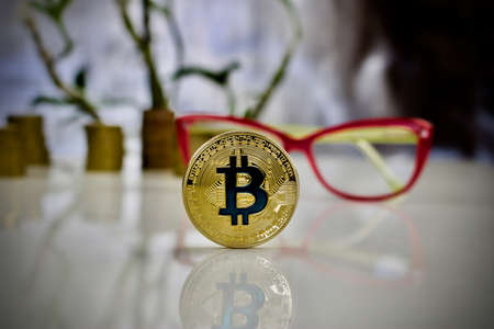 Digital currency physical gold bitcoin coin with blue sign near pink glassesの写真素材
