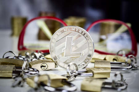 Cryptocurrency physical silver litecoin coin near gold padlocks and pink glassesの写真素材