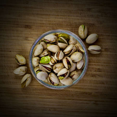 Pistachios nuts glass concept on old wooden boardの写真素材