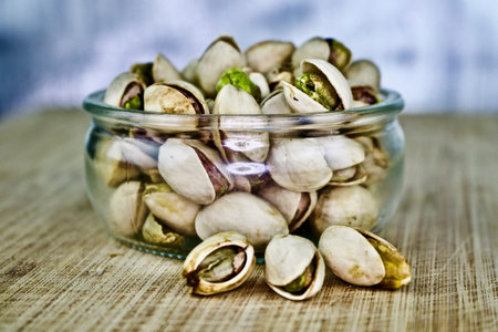 Pistachios nuts in small glass on the wooden old board