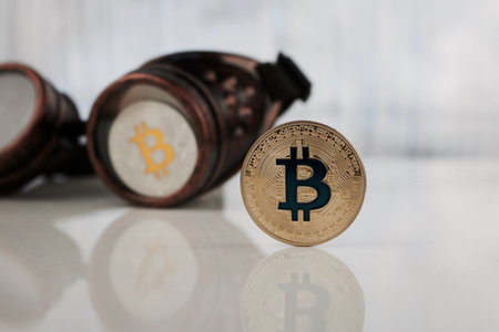 Cryptocurrency physical gold and silver bitcoin coin near steampunk glasses.