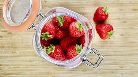 Fresh red strawberries in big kitchen jar on the wooden board.の写真素材
