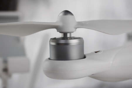 White drone arm with silver small engine and air screw on the top.の写真素材