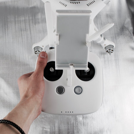 White big drone controller in hand near white quadcopter.の写真素材