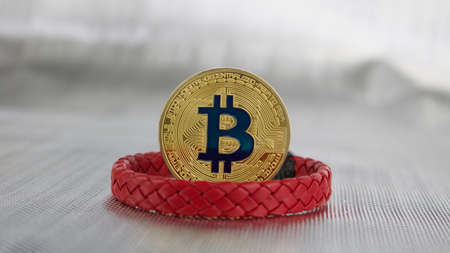 Cryptocurrency physical gold bitcoin coin and red bracelet.のeditorial素材