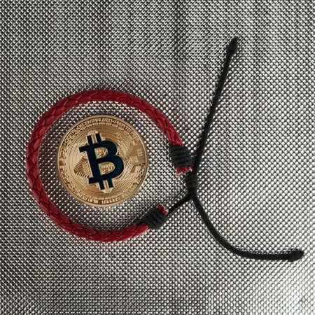 Digital currency physical gold bitcoin coin near red braceletのeditorial素材