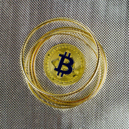 Cryptocurrency physical gold bitcoin coin near gold blink rings.のeditorial素材