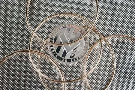 Cryptocurrency physical silver Litecoin coin under gold ringsのeditorial素材