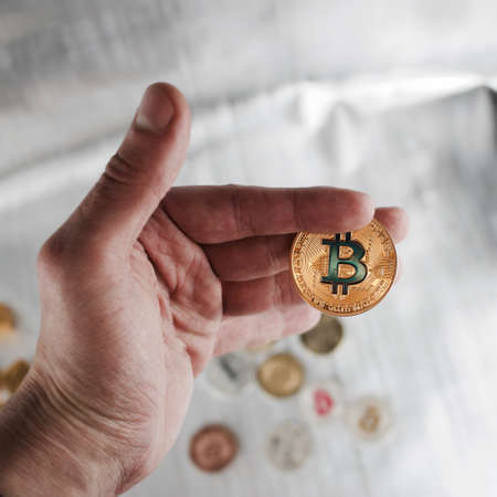 Digital currency physical gold bitcoin coin in man hand.の写真素材