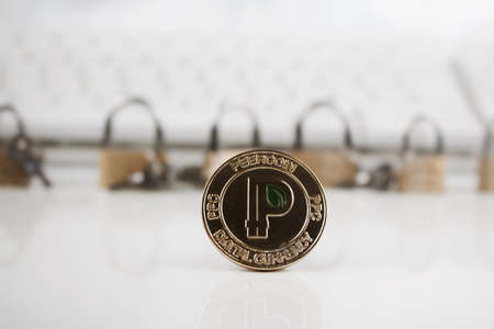 Cryptocurrency physical gold peercoin coin near gold padlocks and keyboard.の写真素材