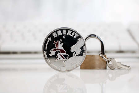 Physical silver brexit coin near gold padlock.の写真素材