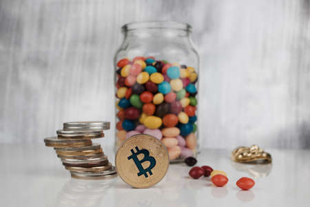 Digital currency physical gold bitcoin coin on the table near jelly sweets.のeditorial素材
