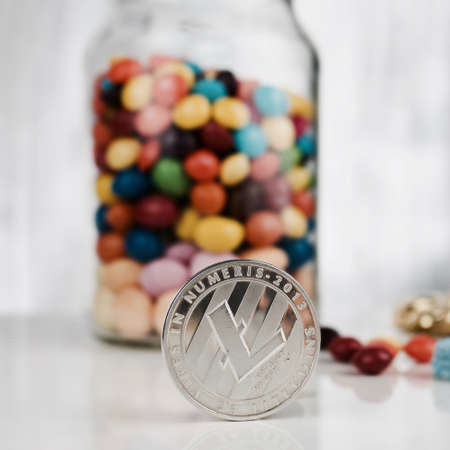Digital currency physical silver Litecoin coin near sweets jar.のeditorial素材