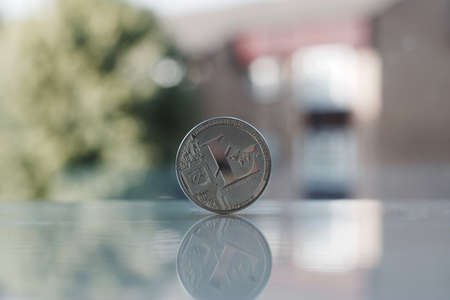Digital currency physical silver Litecoin coin on the table near the window.のeditorial素材