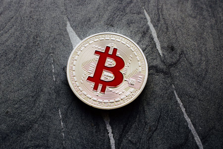 Digital currency physical silver bitcoin coin with red sign on the granite.