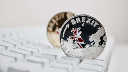 Europe leaving. Brexit physical coin on the white keyboard. British map.の写真素材