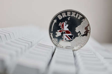 Europe leaving. Brexit physical coin on the white keyboard. British map.の写真素材