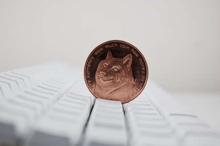 Cryptocurrency physical brass dogecoin coin on the white computer keyboard.の写真素材