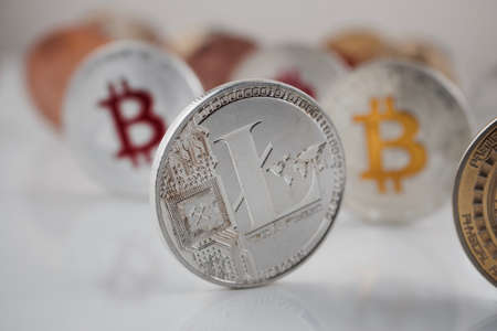 Cryptocurrency physical silver Litecoin coin near colorful bitcoins on white table.の写真素材