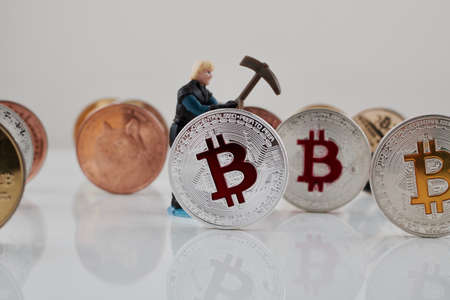 Cryptocurrency physical silver bitcoin coin near coins and miner. Bitcoin mining.の写真素材