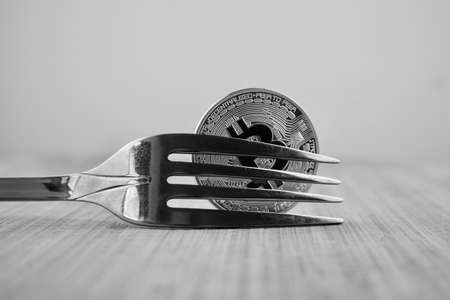 Cryptocurrency physical silver bitcoin coin and fork on wooden board.の写真素材