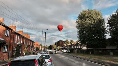 Big red balloon over the road near green tree in Newport Pagnell. Bedfordshire. England.のeditorial素材
